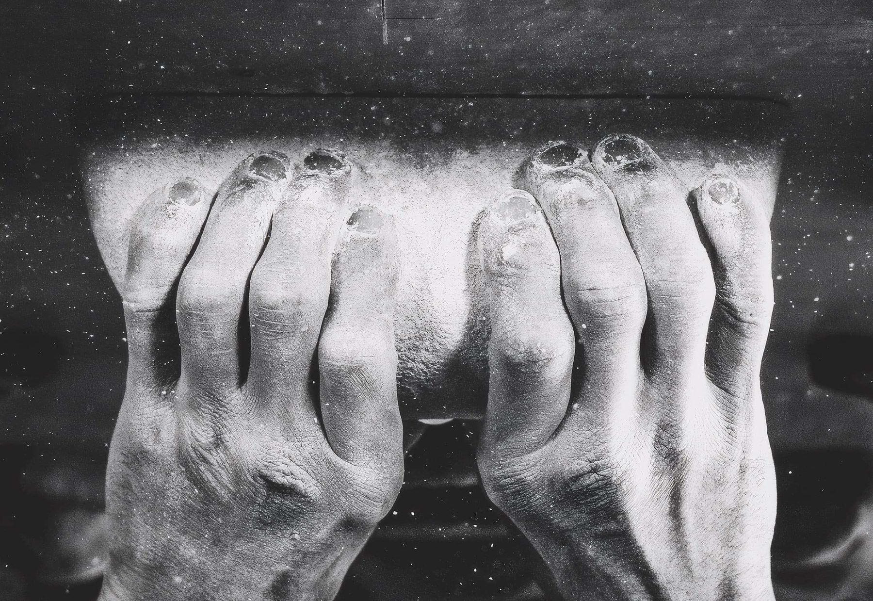 Chalked fingers gripping a training edge